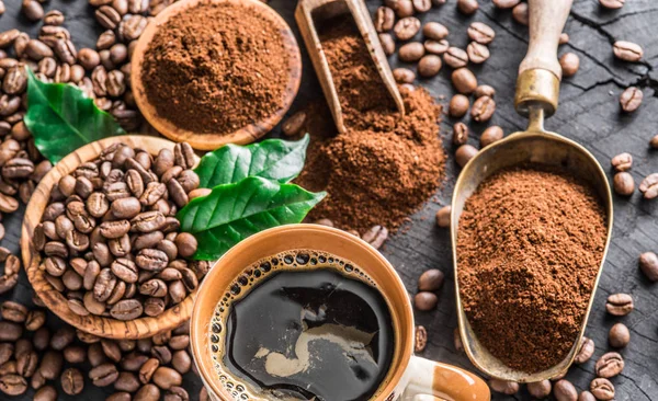 Grãos de café torrados, café moído e xícara de café em madeira — Fotografia de Stock