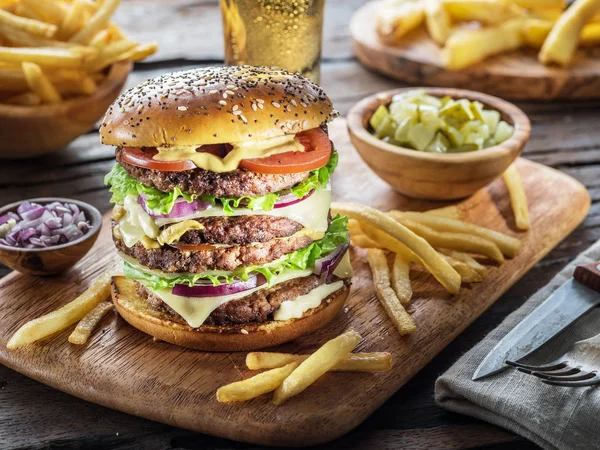 Hambúrguer grande e batatas fritas na bandeja de madeira . — Fotografia de Stock