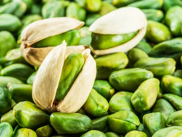 Green pistachio nut with shell over lot of pistachios. — Stock Photo, Image