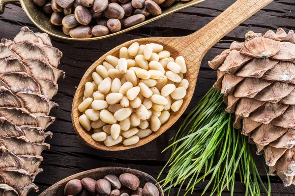 Pinienkerne im Löffel und Pinienkerne auf dem Holztisch. oder — Stockfoto