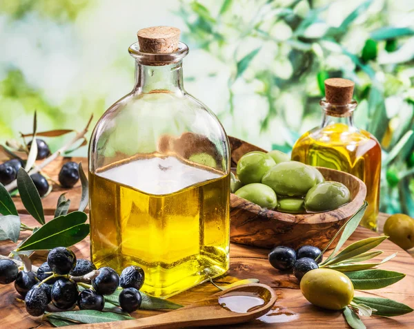 El aceite de oliva y las bayas están en la mesa de madera debajo del tr de oliva —  Fotos de Stock