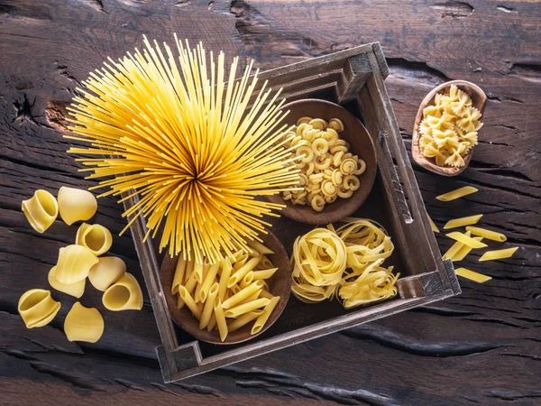 Verschillende pasta vormen op de houten tafel. Bovenaanzicht. — Stockfoto
