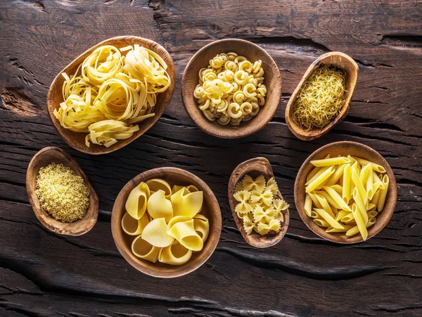 Jenis pasta yang berbeda dalam mangkuk kayu di atas meja. Tampilan atas . — Stok Foto