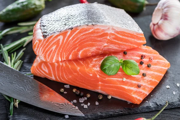 Fresh salmon fillets on black cutting board with herbs and spice — Stock Photo, Image