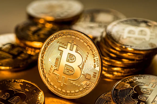 Glanzende fysieke bitcoins op gouden achtergrond. Blockchain technol — Stockfoto