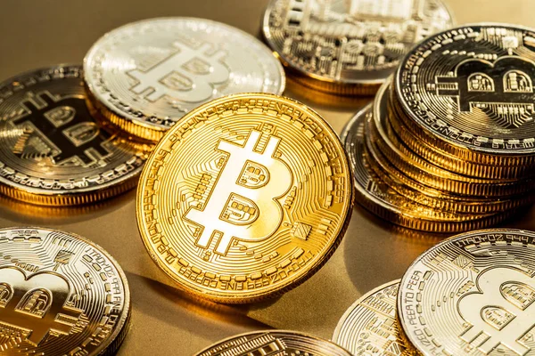 Glänsande fysiska bitcoins på gyllene bakgrund. Blockchain teknolo — Stockfoto