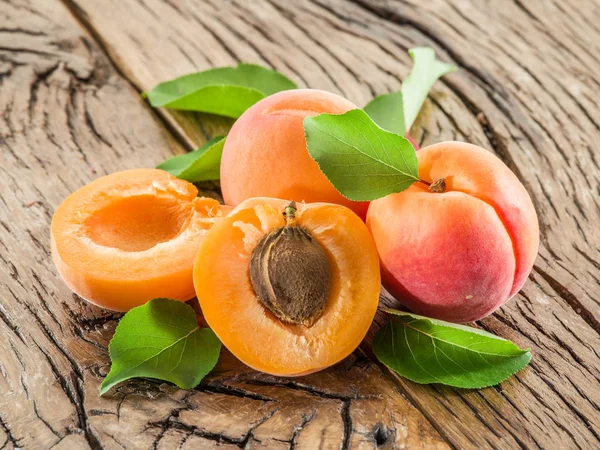 Apricots and its cross-section on the old wooden table. — Stock Photo, Image