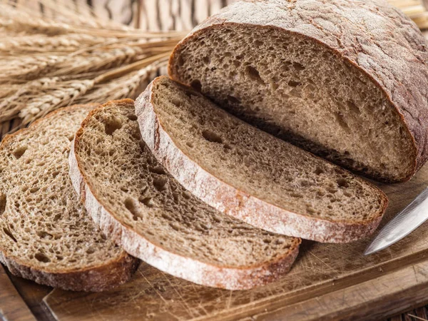 Skivad svart bröd på plankan. — Stockfoto