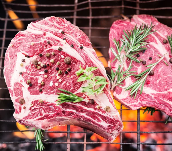 Filetes de costilla y parrilla con fuego ardiente detrás de ellos . — Foto de Stock