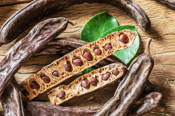 Vainas de algarroba y algarrobas en la mesa de madera . — Foto de Stock