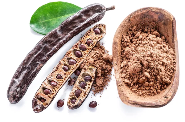 Carob pods och carob pulver i träskål. — Stockfoto