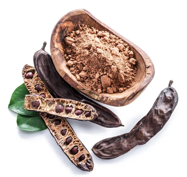 Carob pods och carob pulver i träskål. — Stockfoto