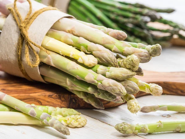 Bundels van groene en witte asperges op een houten bord. Biologische fo — Stockfoto