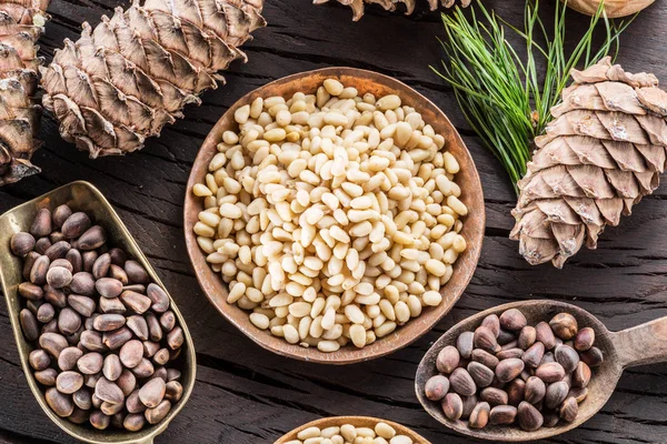 Des pignons dans le bol et des cônes de pignons sur la table en bois. Ou — Photo