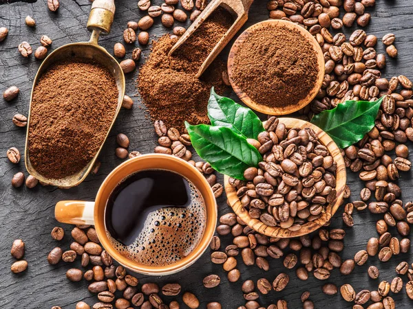 Roasted coffee beans, ground coffee and cup of coffee on wooden — Stock Photo, Image