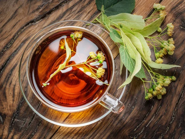Kopp linden te och lime blommor på tabellen trä. — Stockfoto