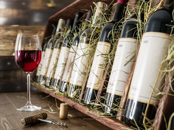 Glas rode wijn en wijn flessen op de achtergrond. — Stockfoto