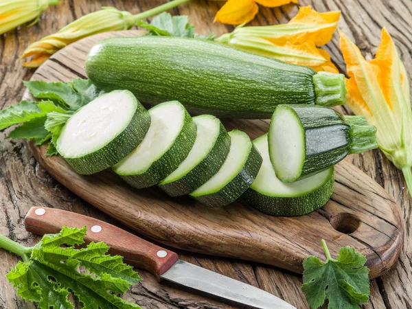 Zucchini with slices and zucchini flowers on a wooden table. — Stock Photo, Image