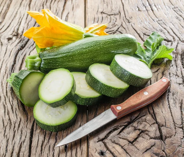 Calabacín con rodajas y flores de calabacín en una mesa de madera . — Foto de Stock