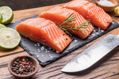 Otlar, baharatlar ile siyah kesme tahtası üzerinde taze somon fileto