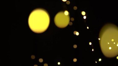 Odaksız bokeh sarı noel ışıkları yavaşça siyah arkaplanda hareket eder.