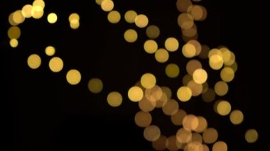 Odaksız bokeh sarı noel ışıkları yavaşça siyah arkaplanda hareket eder.