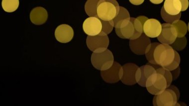 Odaksız bokeh sarı noel ışıkları yavaşça siyah arkaplanda hareket eder.