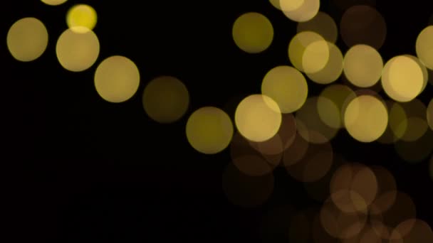 Defokussierte Bokeh Gelbe Weihnachtsbeleuchtung Bewegt Sich Langsam Über Schwarzen Hintergrund — Stockvideo