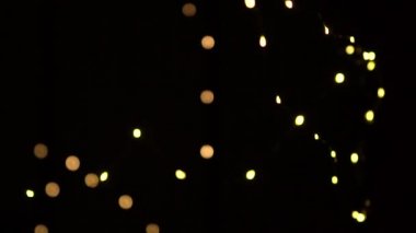 Odaksız bokeh sarı noel ışıkları yavaşça siyah arkaplanda hareket eder.