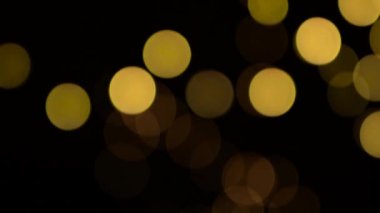 Odaksız bokeh sarı noel ışıkları yavaşça siyah arkaplanda hareket eder.