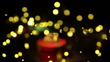 Kırmızı hediye kutularıyla Noel arkaplanı. Amera hediyeye yavaşça yaklaşıyor, ön planda ve arka planda Noel ışıklarıyla güzel Bokeh..