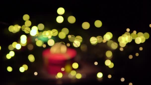 赤いギフトボックス付きのクリスマスの背景 カメラはゆっくりと贈り物に近づき前景と背景はクリスマスライトの美しいボケ — ストック動画