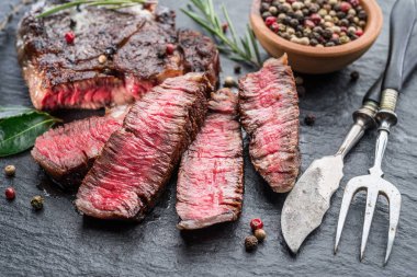 Medium rare Ribeye steak with herbs on graphite board. clipart