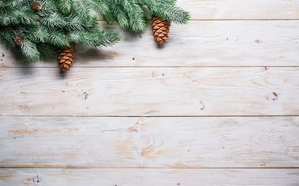 Snöig gran gren med gran koner på träbord. Jul eller nyår — Stockfoto