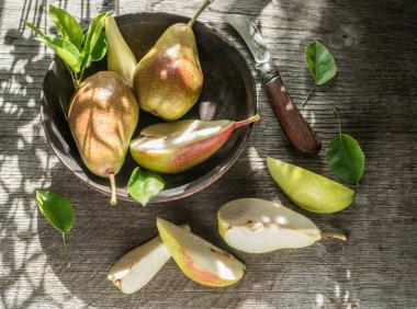 Bahçedeki ahşap masada olgun armutlar tabakta. Üst görünüm.