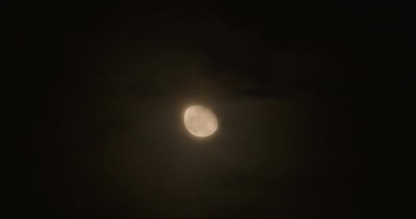 Lune incomplète se déplace dans le ciel nocturne, accompagnée de petits nuages .