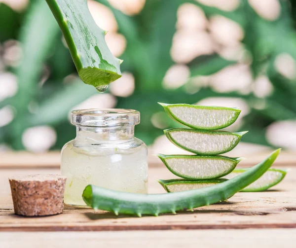 Fresh aloe leaves and aloe gel in the cosmetic jar on wooden tab — Stock Photo, Image