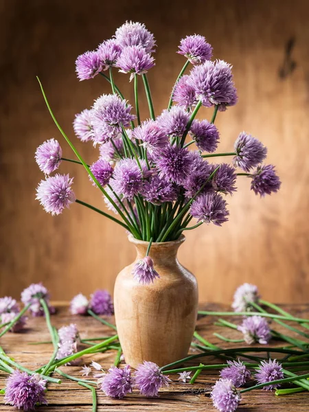 Bouquet of onion (chives) flowers in the vase on the wooden tabl Stock Picture