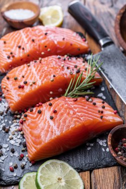 Otlar, baharatlar ile siyah kesme tahtası üzerinde taze somon fileto