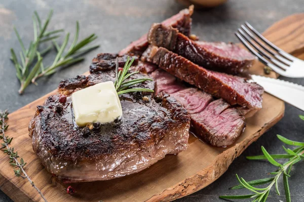 Steak de Ribeye moyen et rare avec des herbes et un morceau de beurre sur le — Photo