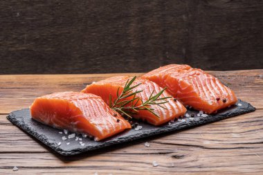 Otlar ve baharatlar ile siyah kesme tahtası üzerinde taze somon fileto. Close.