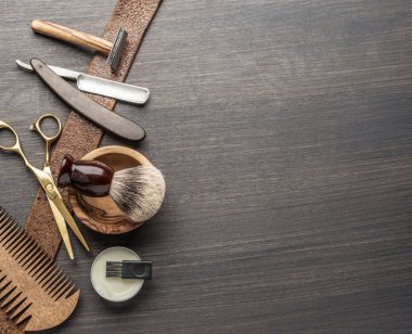 Ahşap arka planda klasik kuaför ve kuaför aletleri. Koyu renk ahşap masada duran berber dükkanının enstrümanlarının üst görüntüsü.