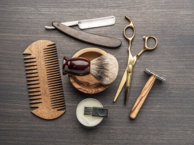 Ahşap arka planda klasik kuaför ve kuaför aletleri. Koyu renk ahşap masada duran berber dükkanının enstrümanlarının üst görüntüsü.
