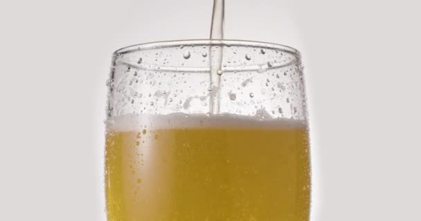 白を基調とした軽ビールのグラス ジェットはゆっくりとビールでガラスを満たし 豊富な泡と泡を引き起こす 時計回りの回転 — ストック動画