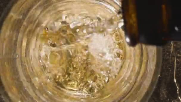 Verser de la bière dans un verre. Vue d'en haut. Un jet de bière est versé dans le verre, couvrant le fond avec de la mousse et élevant le niveau au sommet du verre.