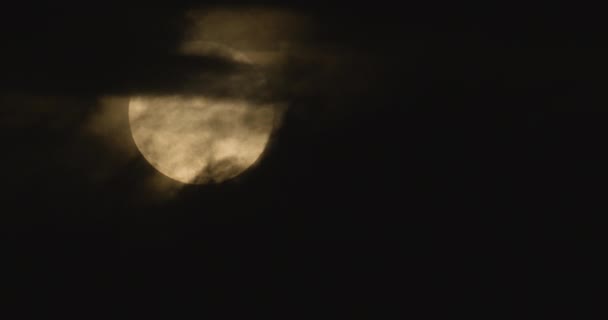 La pleine lune se déplace dans le ciel nocturne, accompagnée de petits nuages .