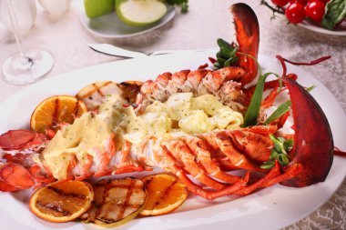 Elma soslu fırında ıstakoz ve restoranda beyaz bir tabakta ızgara bbq meyvesi..