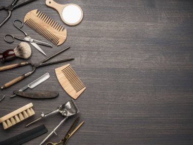 Ahşap arka planda klasik kuaför ve kuaför aletleri. Koyu renk ahşap masada duran berber dükkanının enstrümanlarının üst görüntüsü.