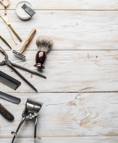 Classic grooming and hairdressing tools on wooden background. Top view on barbershop instruments  laying on white wooden table.