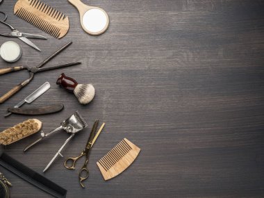 Ahşap arka planda klasik kuaför ve kuaför aletleri. Koyu renk ahşap masada duran berber dükkanının enstrümanlarının üst görüntüsü.